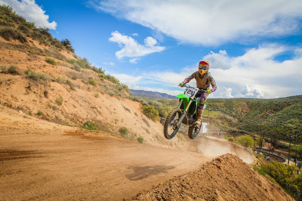 heros-img Exciting motocross action with a biker jumping on a dirt track during a race.